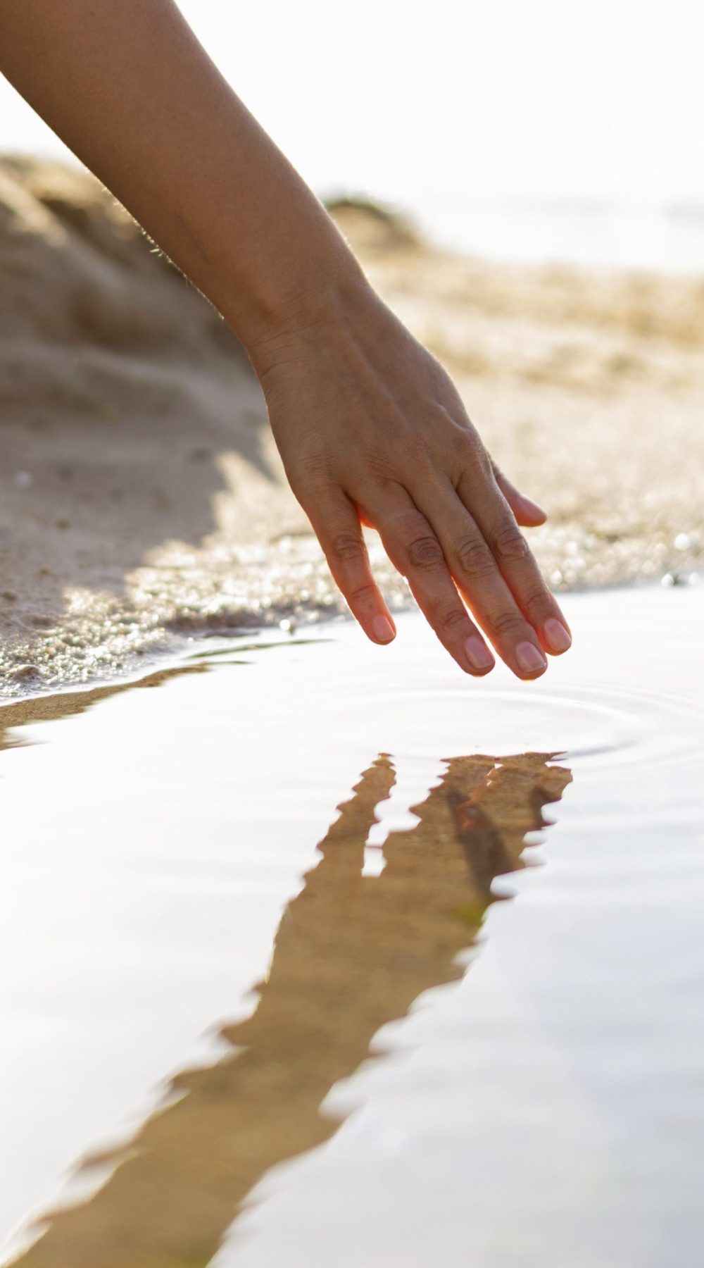 woman-running-her-hand-through-water-beach
